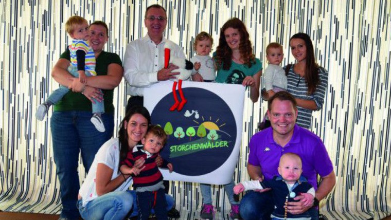 Eltern mit Kindern mit Logotafel Storchenwälder